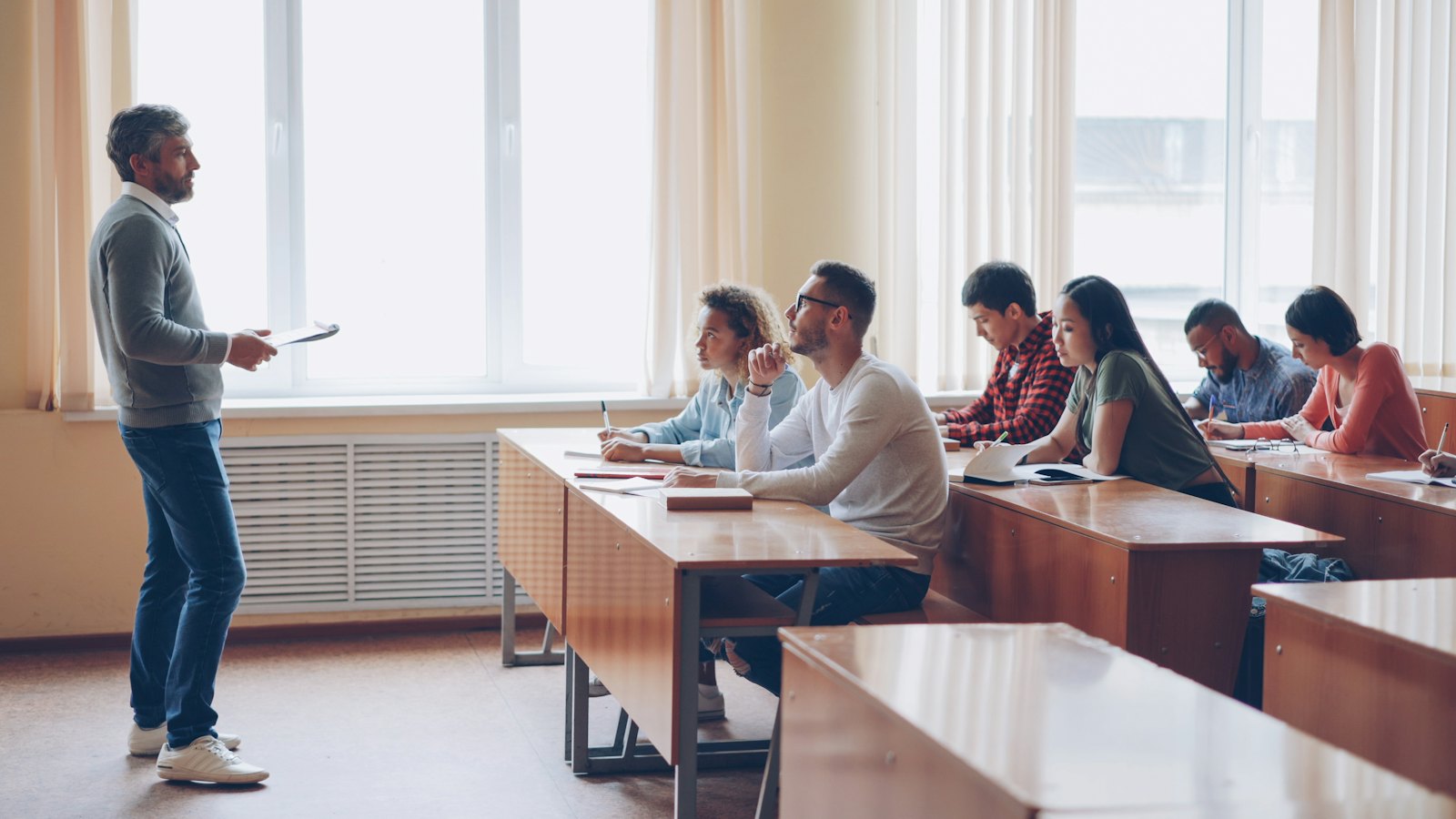 An instructor speaking to students in a classroom lecture.